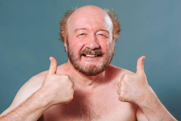 istock Front view an aged senior man in the studio on a blue background shows a gesture thumb up smile joy. 2149683156