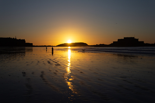 Walk on a beach of Saint-Malo at sunset time (Brittany, France)