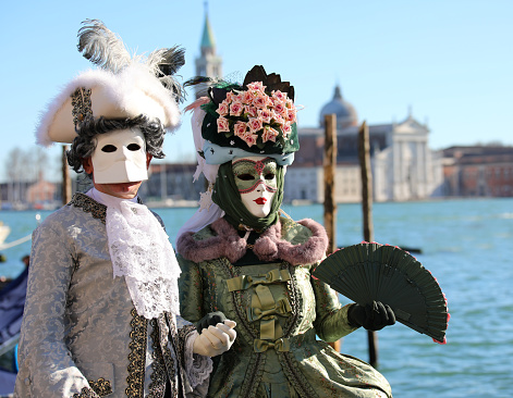 Venice, VE, Italy - February 13, 2024: noble man and woman dressed in masks during the carnival and the sea