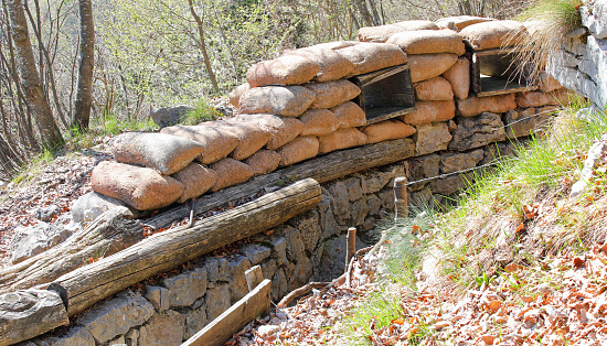 old narrow trench dug in the ground and lined with sandbags to protect soldiers from enemies