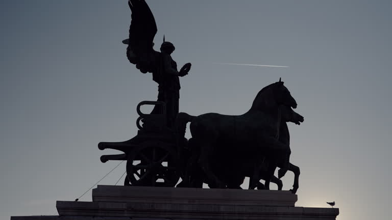 The quadriga statue dedicated to the freedom of citizens on the terrace of the Vittoriano called Altare della patria in Rome, Italy at sunset