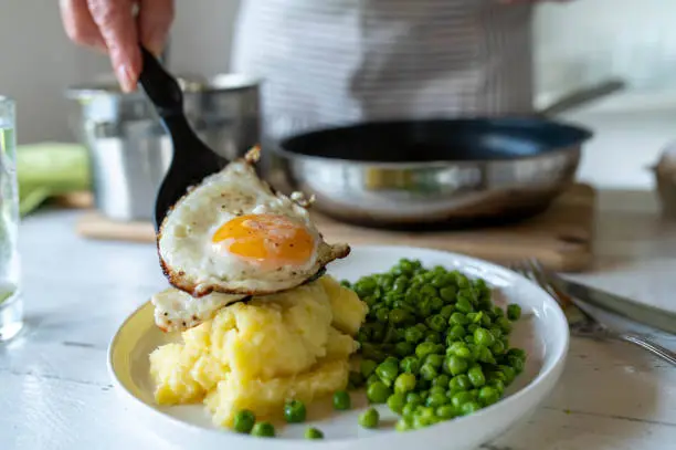 Fried egg with mashed potatoes and green peas for healthy vegetarian dinner or lunch in the kitchen