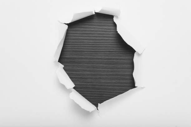 istock Torn hole in white paper revealing gray wood background. Space for text. 2149687273