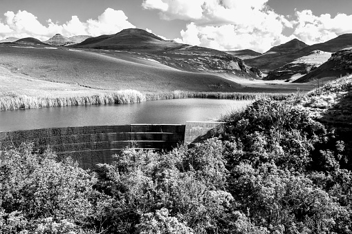 Black and White view of a small mountain Reservoir, with the Majestic Drakensberg Mountains in the Background, in the Golden Gate Highlands National Park of South Africa.