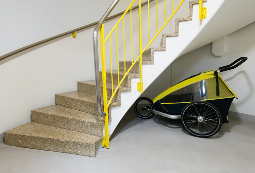 Bicycle trailer for children parked under the stairs of an apartment building