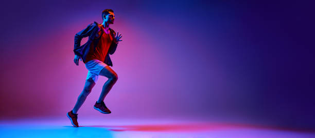 istock Active young man, athlete in sportswear in motion training, running on gradient pink purple background in neon light 2149687902