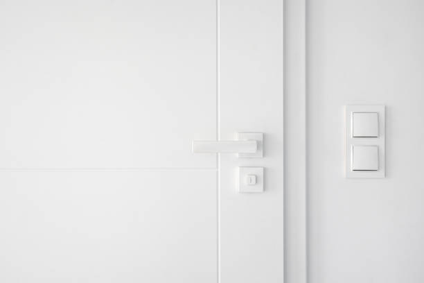 istock Light switches on white wall near closed room door with mechanical handle 2149688082
