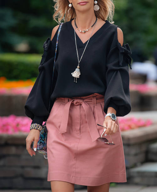 Urban summer clothes. A black blouse with bows and open shoulders, a powder pink denim skirt and stylish accessories. Stylish girl in a black blouse with a V-neck and wide long puffed sleeves. white shirt black skirt stock pictures, royalty-free photos & images