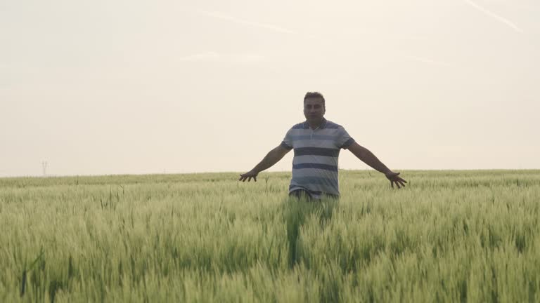 Happy free farmer running in wheat agricultural field, slow motion