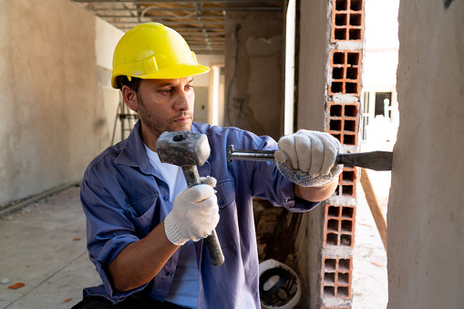 Latin American construction worker working at a building site using a chisel