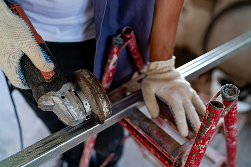 Close-up on a construction worker cutting a metal piece using an electric saw