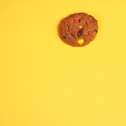 A single object of rainbow chips cookies on yellow desk
