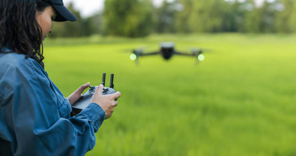 istock A female farmer wearing a hat stands and controls a drone in a green wheat field. Modern technology in digital agriculture 2149690084