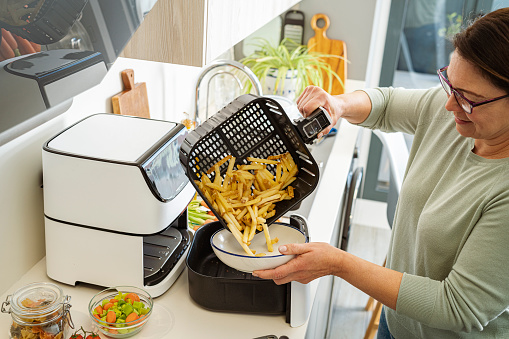 Woman cooking french fries in air fryer