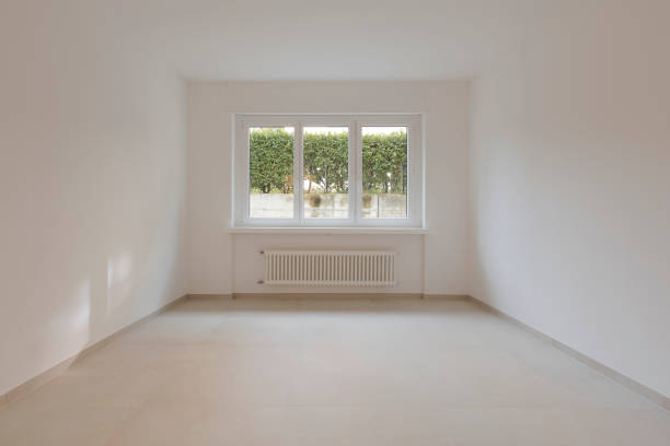 istock Empty interior of a room, with a central window in the background. Under the window a radiator. 2149690509