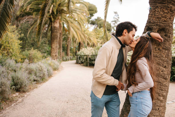 A young tourist kissing in Park Guell, on vacation. Visiting Spain during springtime. Falling in love in Park Guell