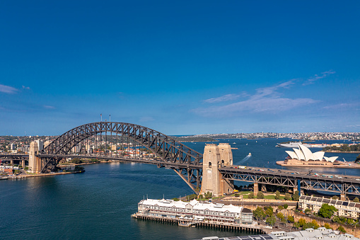 Panoramic view of Sydney Arch Bridge across the Tasman Sea behind the modern buildings of city.