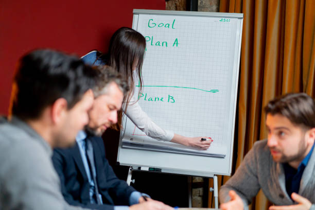 istock office workers sitting in conference room with red walls headed by the director actively discussing the schedule 2149691868