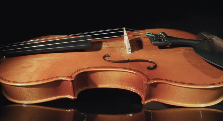 Cinematic shot of antique violin isolated on dark background seen through notes paper curl