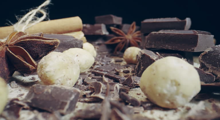 Scene composition consisting of various chocolate bars and pieces, cups of cocoa and hazelnuts, cinemon sticks and dried anise star