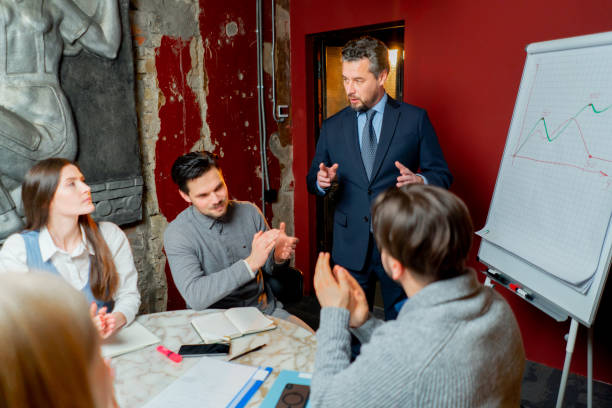 istock Office workers sit in a conference room with red walls and the director explains the drawn up schedule 2149693684
