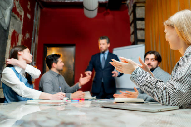 istock Office workers sit in a conference room with red walls and the director explains the drawn up schedule 2149694440