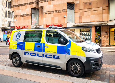 Glasgow, Scotland - Side view of a police van on Queen Street in Glasgow's city centre, with pedestrians on Argyll Street in the background.