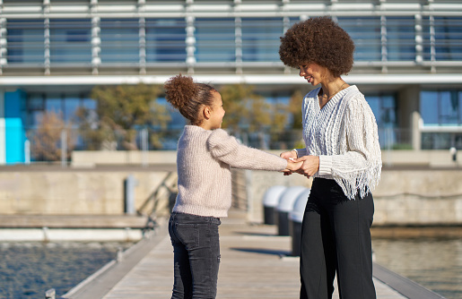 A woman and a child are standing on a dock, the woman is holding the child's hand