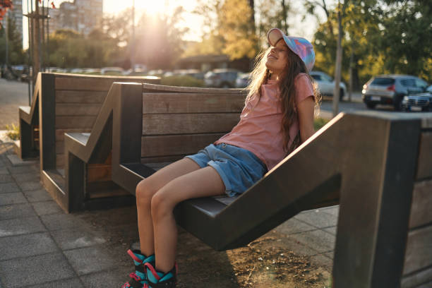 Fitness in modern concrete environments. Beautiful girl is relaxing on sun after riding roller skates.