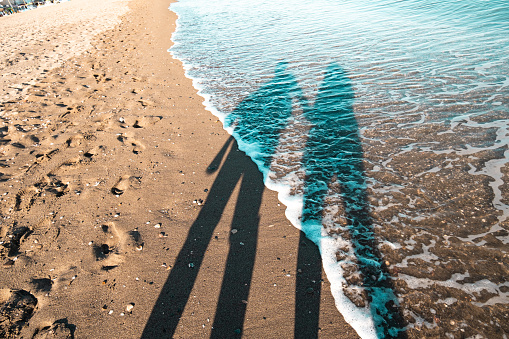 Sunny Spanish beach, shadows figures on the beach sand