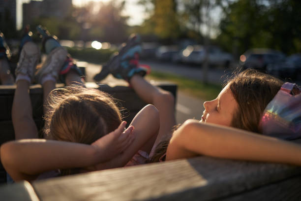 June 24, 2023. Belarusian city of Gomel, Central Park. A group of teenage boys and girls is sitting on the street. Adolescence.