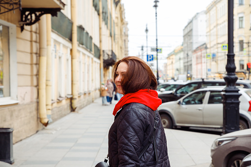 smiling young Caucasian female woman looking at camera on street of european city. positive emotion, tourism, date, love, valentine's day concept. lifestyle waist up portrait of 38 years old woman