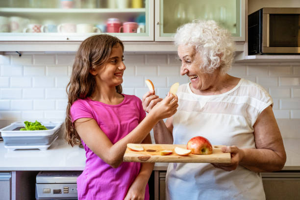 istock grandmother and granddaughter snacking apple in kitchen 2149700024