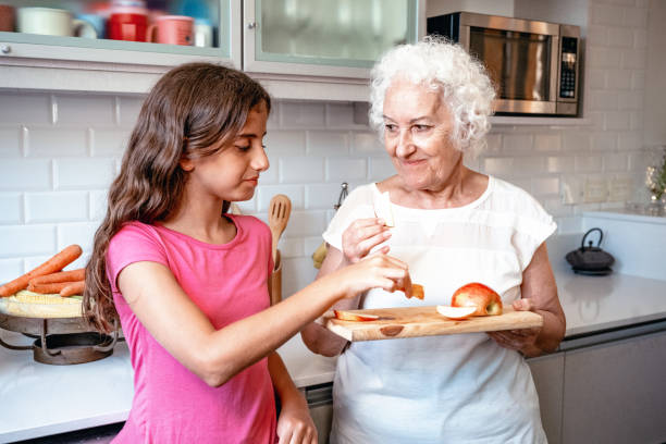 istock grandmother and granddaughter snacking apple in kitchen 2149700086