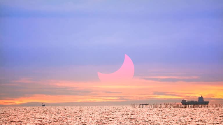 solar eclipse red sunset on the ocean with cargo ship and red orange yellow cloud background time lapse