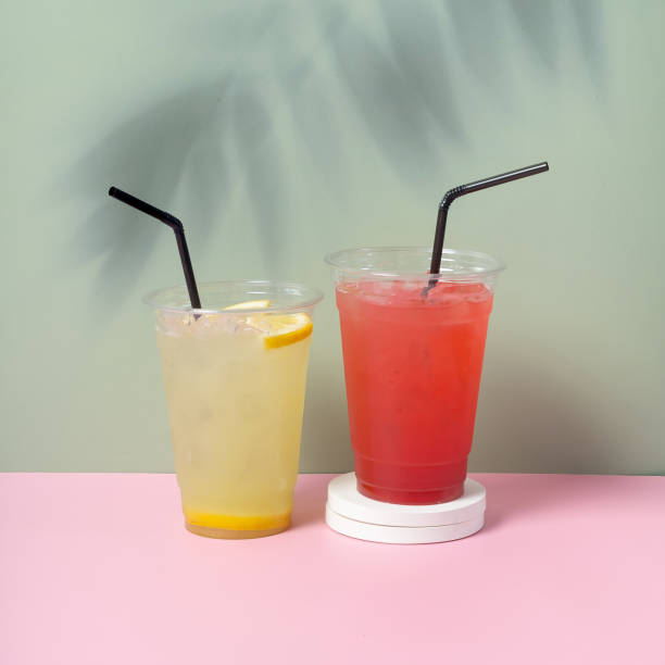 istock Two takeaway glasses of summer drinks with ice. Lemonade on coloured background 2149700308