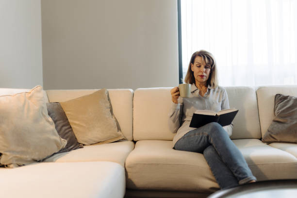 istock Senior woman reading book at home 2149701479