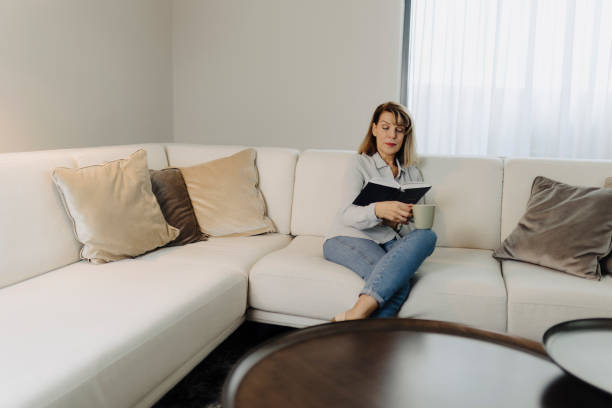 istock Senior woman reading book at home 2149701493