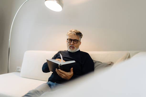 istock Senior man reading book and resting at home 2149701660