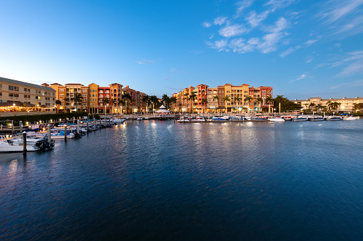 Naples, Florida, USA - February 13, 2024: Twilight settles on Naples with waterfront buildings and boats under a clear sky.