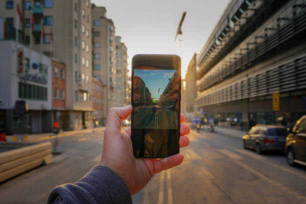 Cropped hand holding a mobile phone against city street