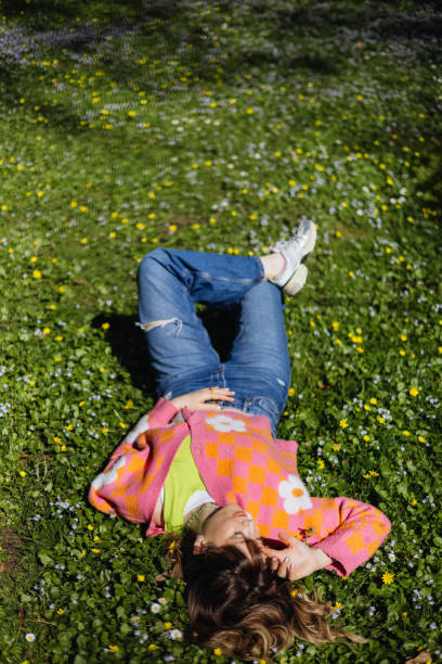istock Springtime Bliss: Beautiful Woman Relaxes with Closed Eyes on Park Grass 2149702030