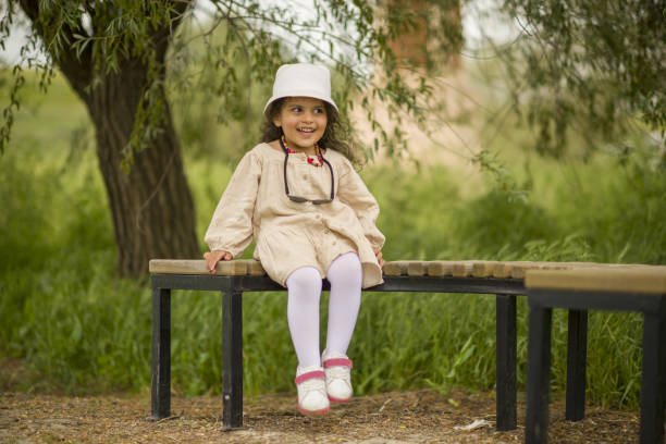 Portrait of a young girl standing on the edge of a small waterfall in the forest. The child likes to touch the cool, clean stream on the hill.