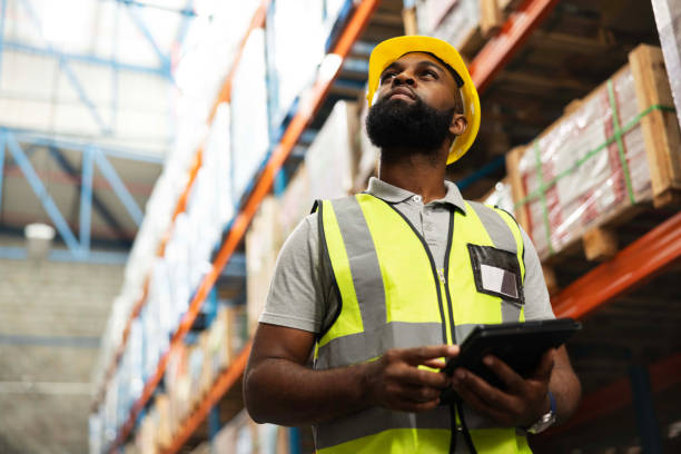 istock Warehouse, engineer and black man with tablet for planning storage, distribution or check stock of freight. Factory, technology and serious worker thinking of shipping, inventory and cargo on app 2149706274