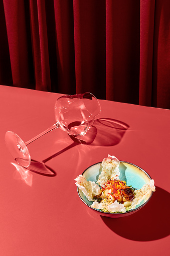 Delicate hummus with rice flour chips in Asian style, presented in a ceramic bowl on a red velvet backdrop, accompanied by a wine glass