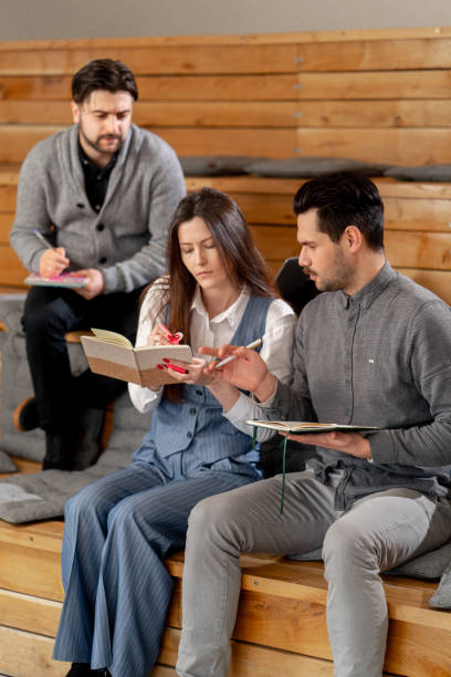 istock three office workers sitting in the lounge area on wooden benches with pillows studying writing in a notebook 2149709591