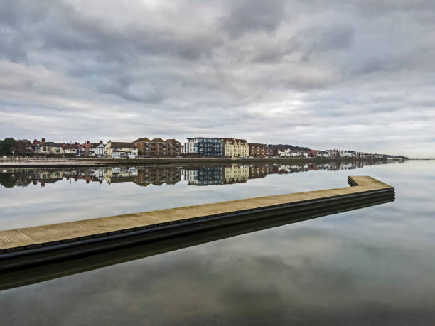 Idyllic riverside neighborhood in southampton, england, with houses reflecting in tranquil water under a clear sky