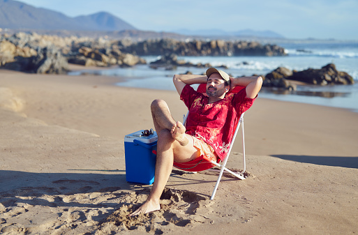 mature man sitting alone with hands on head relaxed enjoying beach and nature