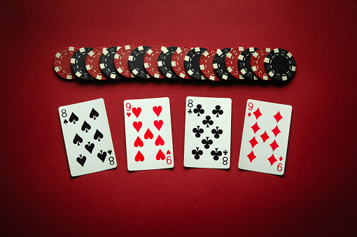 Chips and playing cards with a winning combination of two pairs on a red table. Concept of luck or winning in poker club. Winning at a casino depends on luck.