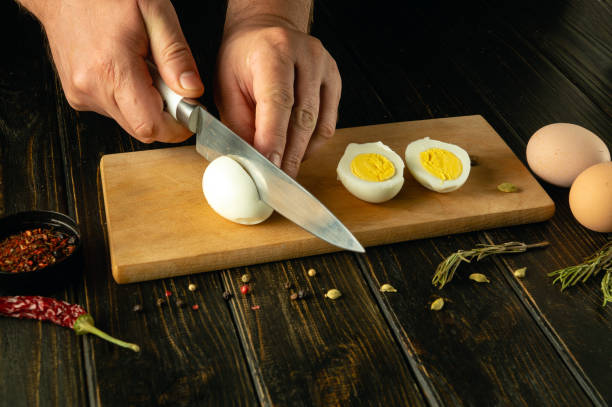 istock A cook cuts a boiled egg with a knife before preparing an eggs dish. Low key calorie diet concept on kitchen table. Place for advertising 2149712188
